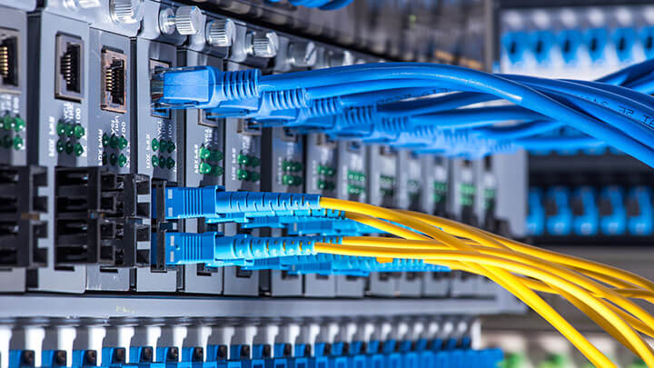 Cabos de rede azuis e amarelos conectados a uma interface de servidor.