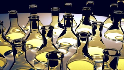 Coleção de frascos de Erlenmeyer transparentes sobre um fundo preto com luz amarela refletindo.