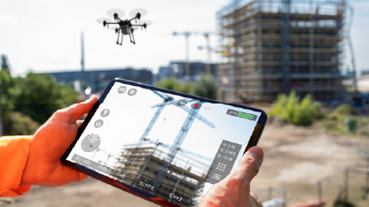 Homem segurando tablet enquanto observa drone